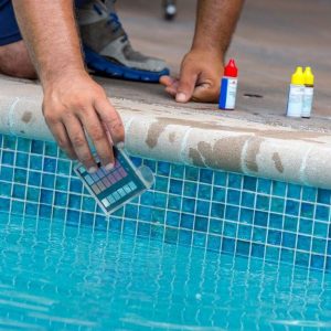 An unrecognizable man is using a pool testing kit to test the chemical levels in a   swimming pool. This is a standard kit used by pool maintenance people and homeowners to test the water to keep it healthy for swimmers. Shot with Canon 5D Mark lll.
