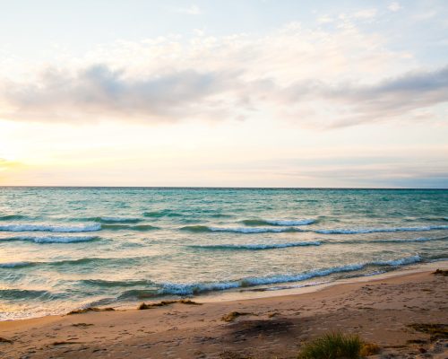 Serene Sunrise Over Lake Michigan Beach Landscape Serene sunrise beach scene along Lake Michigan's Empire shoreline. Soft pastel hues and gentle waves invite tranquility and natural splendor.
