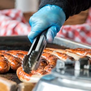 Take away sausaged being grilled at public food market stand.